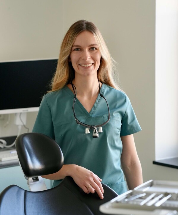Dr. Isabell Jordan steht im Behandlungszimmer und l&auml;chelt in die Kamera.