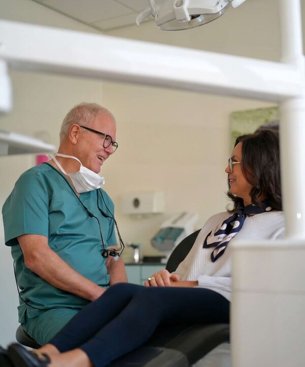 Wolfgang Jordan unterh&auml;lt sich im Behandlungszimmer mit einer Patientin mittleren Alters.