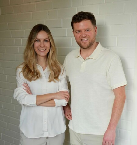 Portraitbild von Isabell Jordan (links) und Erik Jordan (rechts) vor einer wei&szlig;en Wand.