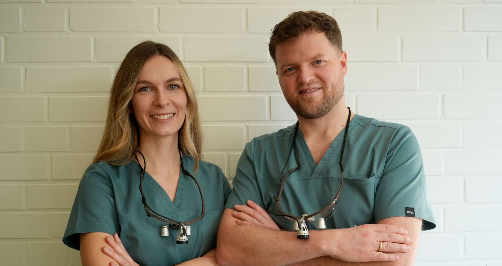 Zweier-Portrait von Isabell Jordan (links) und Erik Jordan (rechts). Beide stehen mit verschr&auml;nkten Armen vor einer wei&szlig;en Wand.