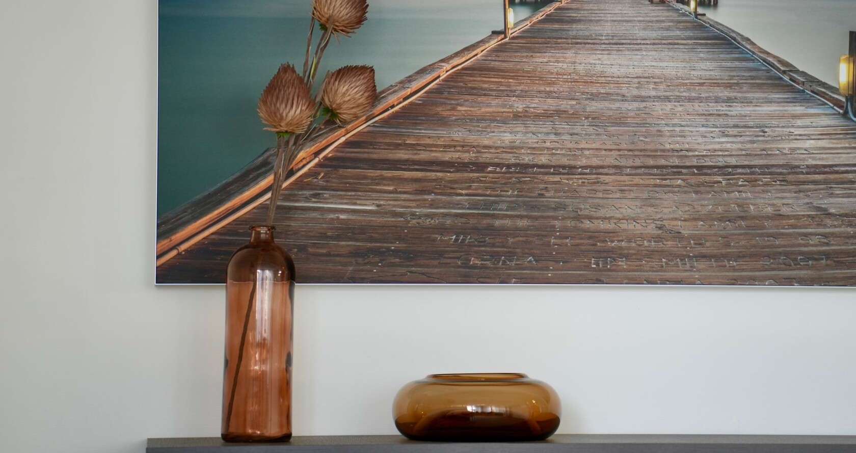 Impressionen aus der Praxis. Vasen und ein Druck von einem Steg an einer wei&szlig;en Wand.